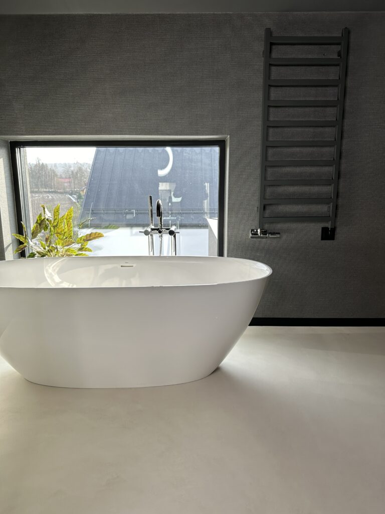 Posadzka z mikrocementu July beige i biała wanna wolnostojąca w łazience domu jednorodzinnego w Krakowie wykonane przez mikrocement-pro